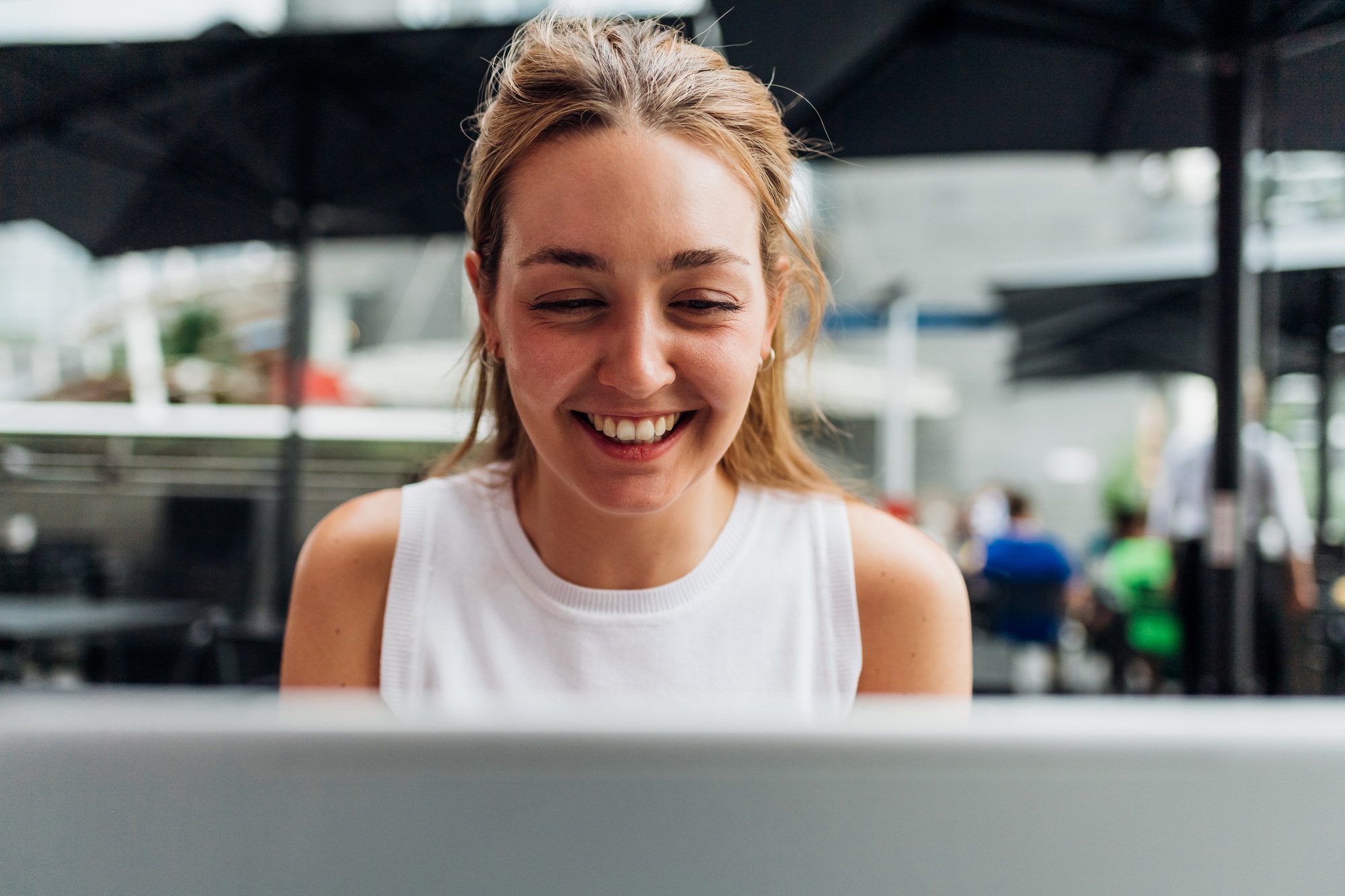 Young caucasian woman sitting outdoors videocalling using computer laughing